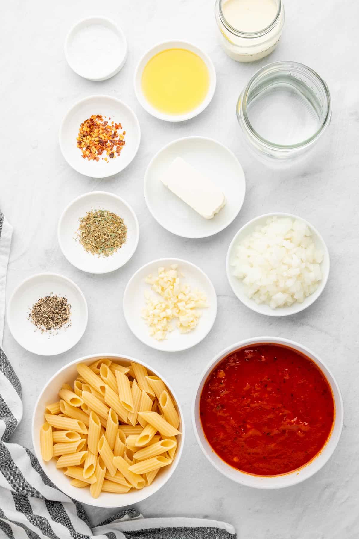 ingredients for the pasta recipe laid out in white dishes and a cloth at the bottom right corner