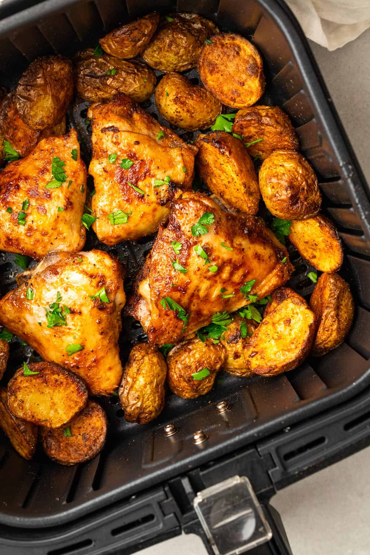 close up of the cooked chicken and potatoes in the air fryer