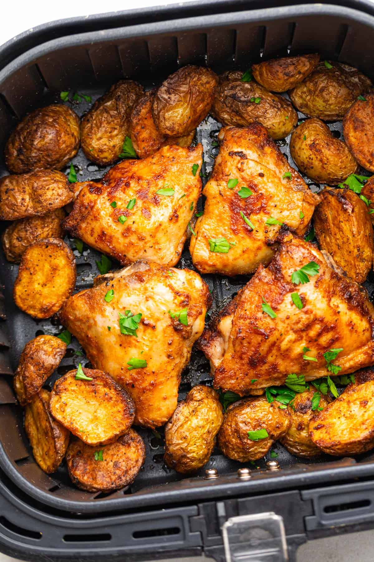 crispy cooked chicken and potatoes in the air fryer basket