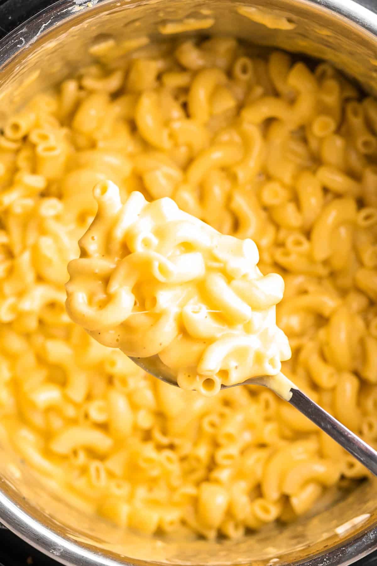 close up of a spoonful of Mac and cheese showing stringy cheese and creamy sauce