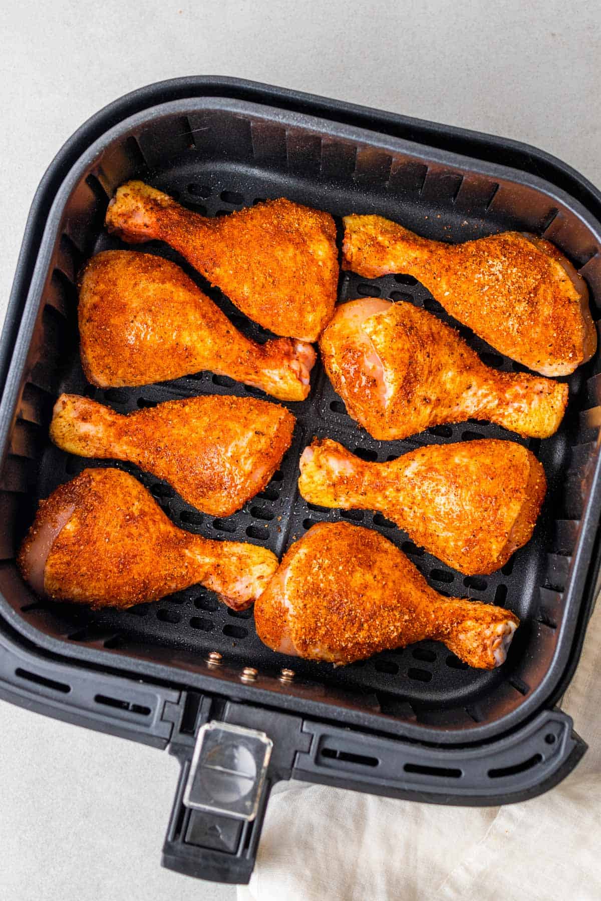 drumsticks laid out in the air fryer basket before cooking them in the air fryer