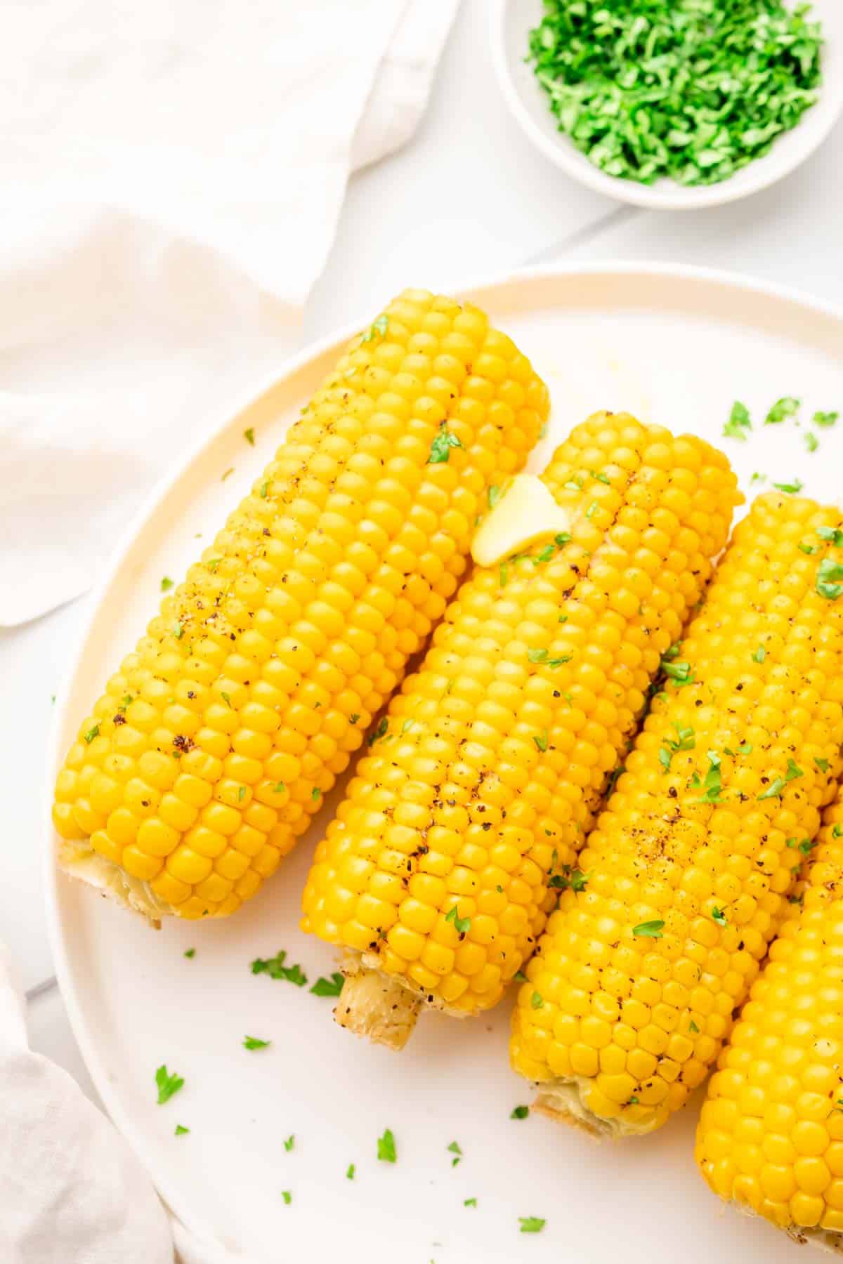 corn on the cobs with melted butter on a white plate