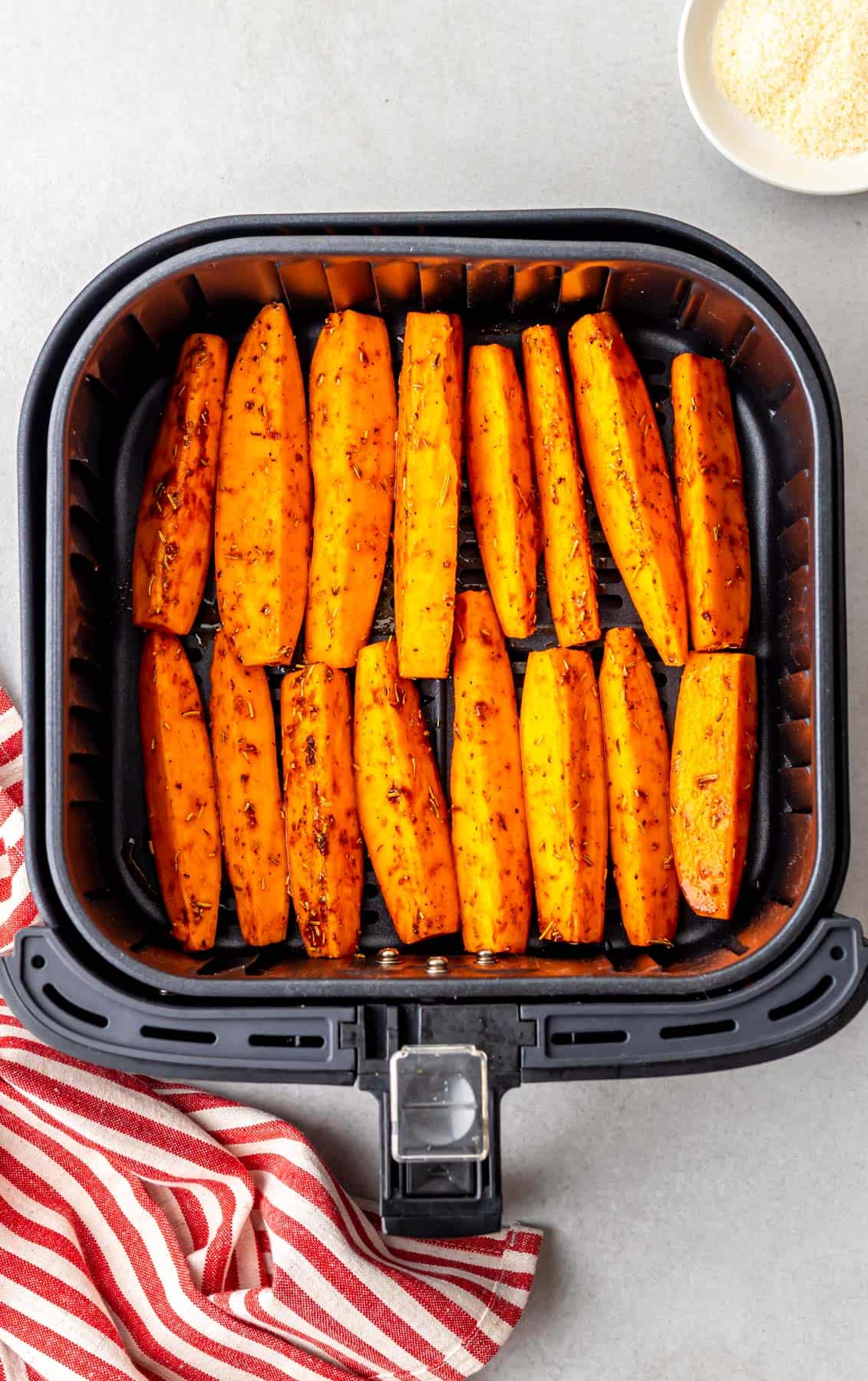 cooked sweet potato wedges in the air fryer laid out in neat rows