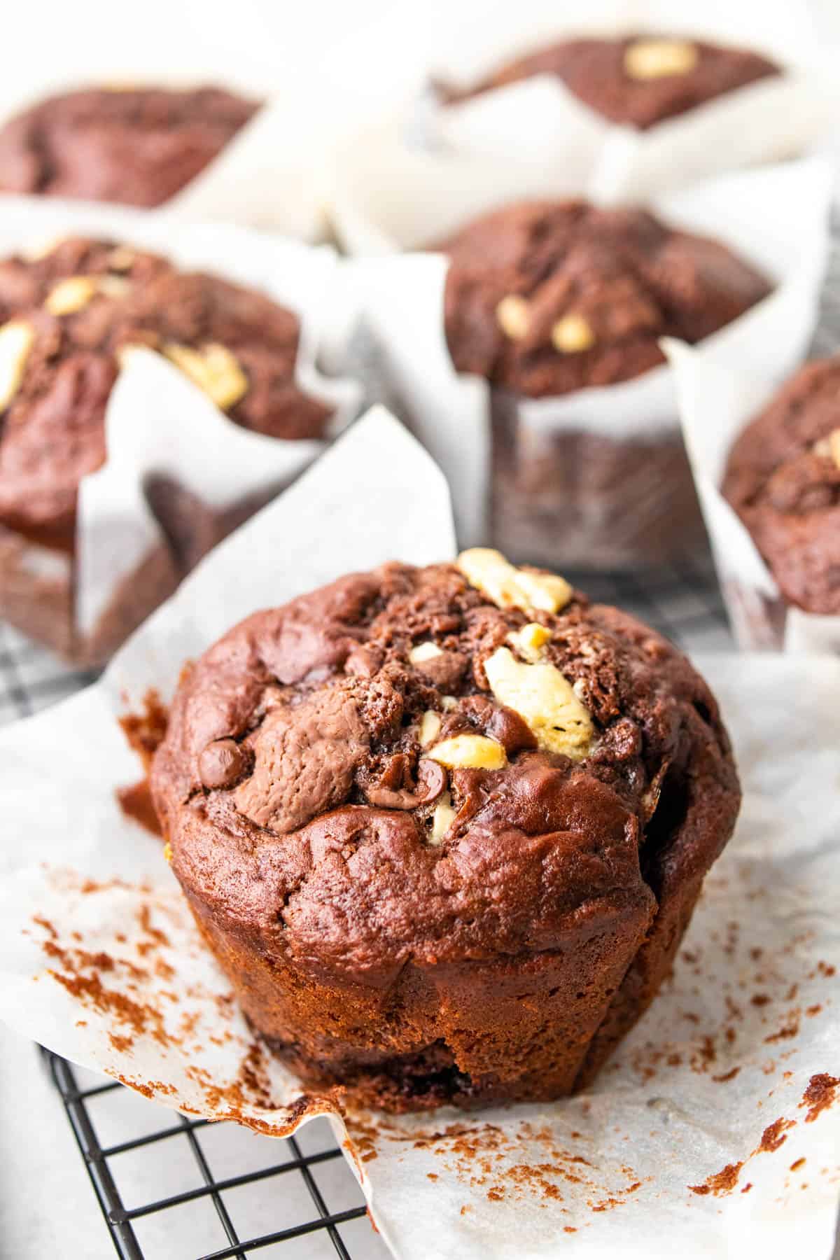 unwrapped chocolate muffin on its wrapper surrounded by other muffins