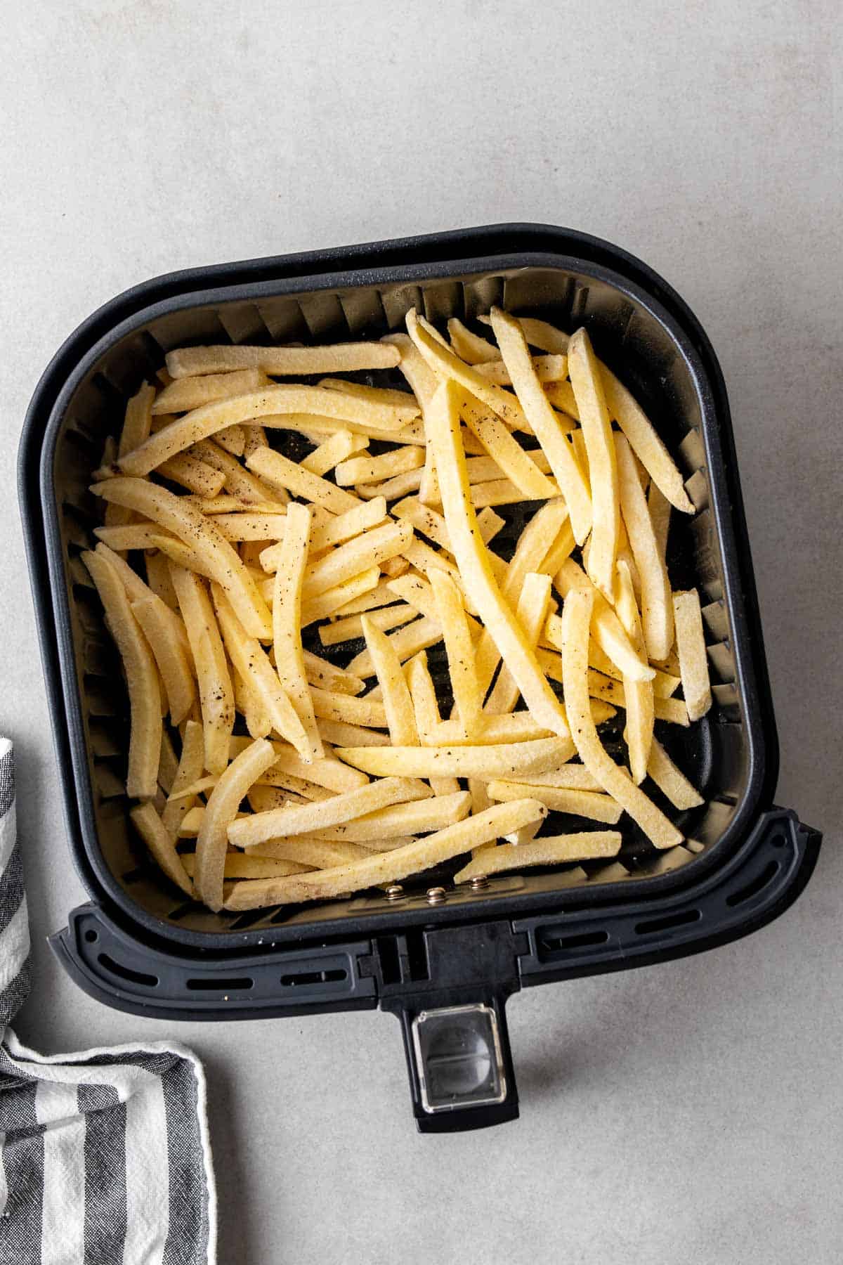frozen French fries in the air fryer ready to be cooked