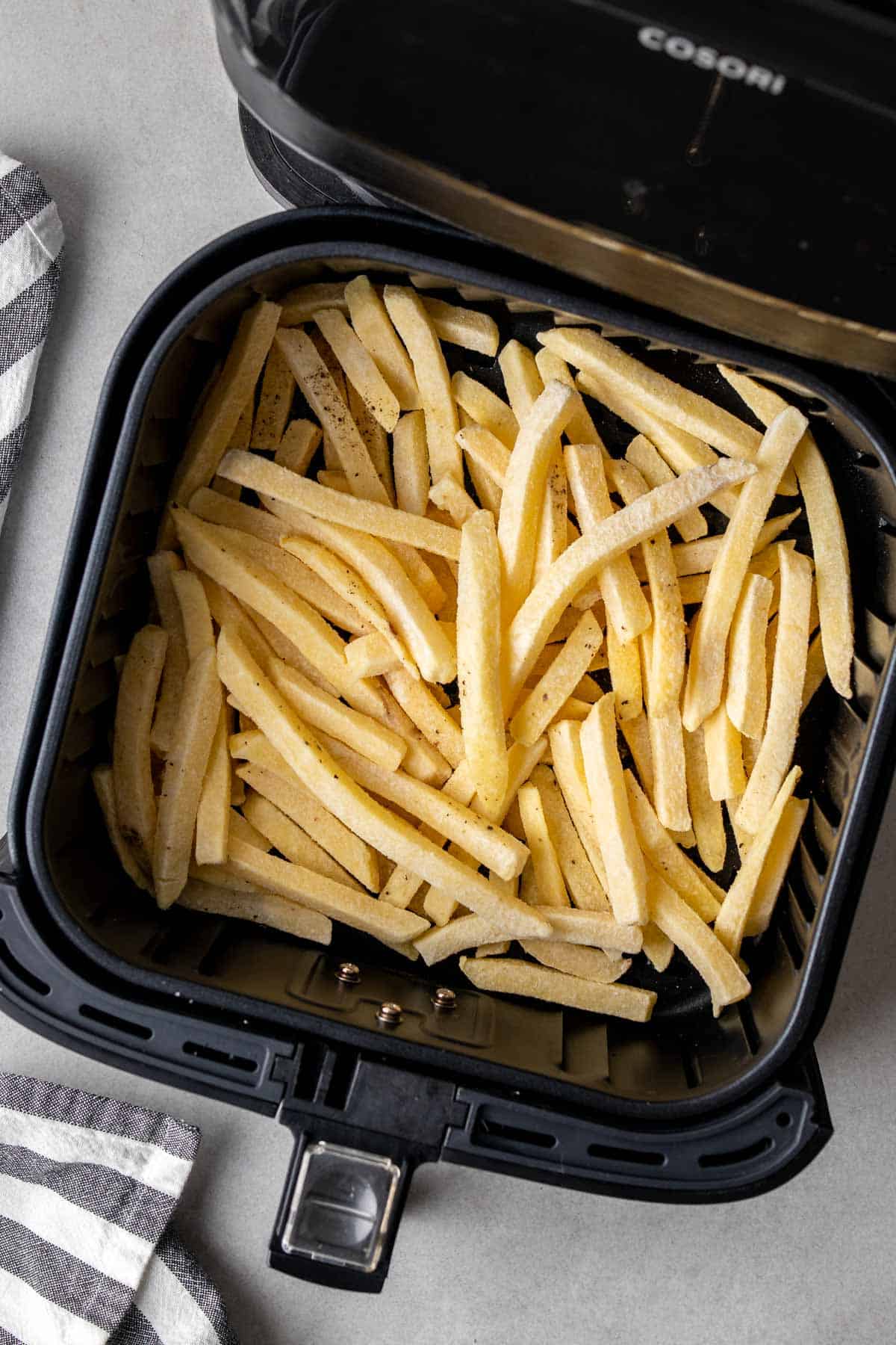 French fries in air fryer basket ready to be pushed into the air fryer