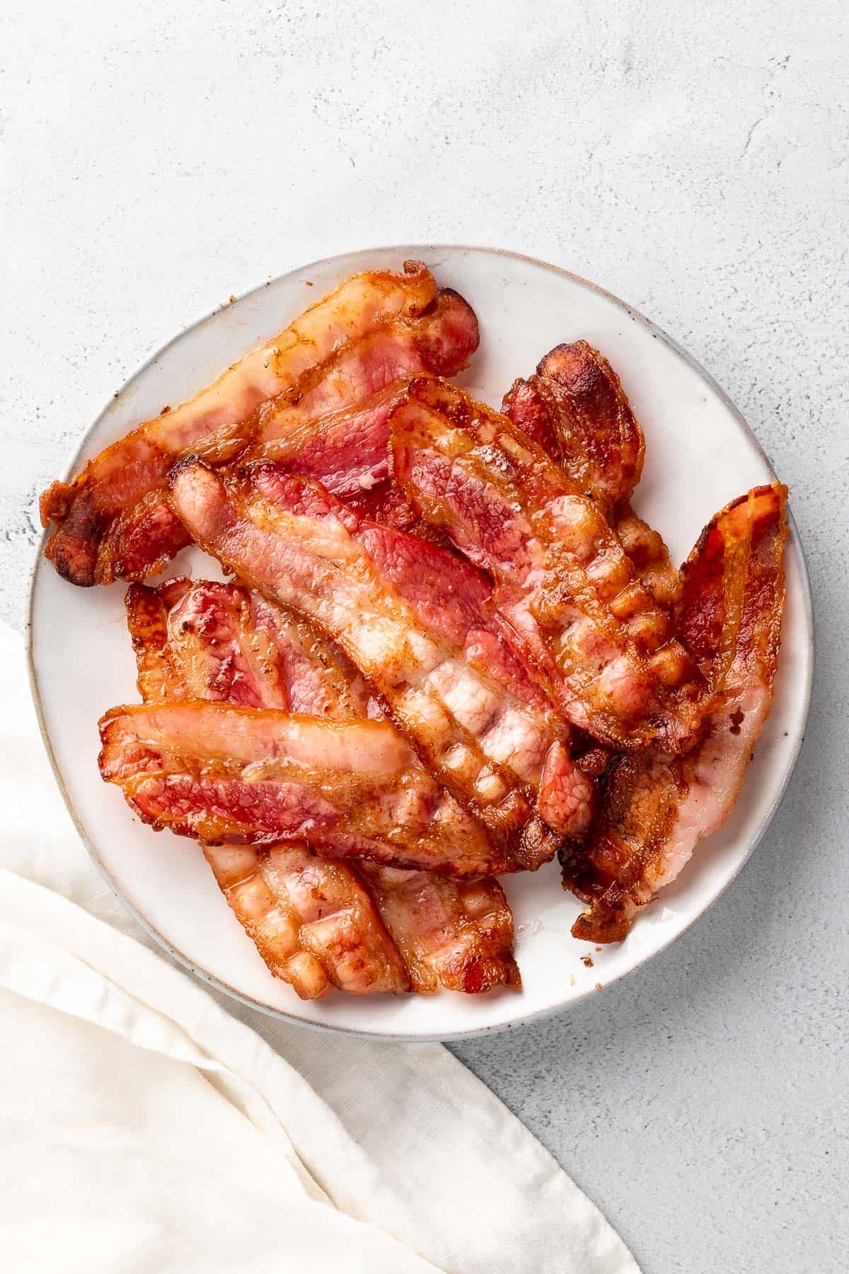 close up of crispy and perfectly cooked strips of bacon on a plate