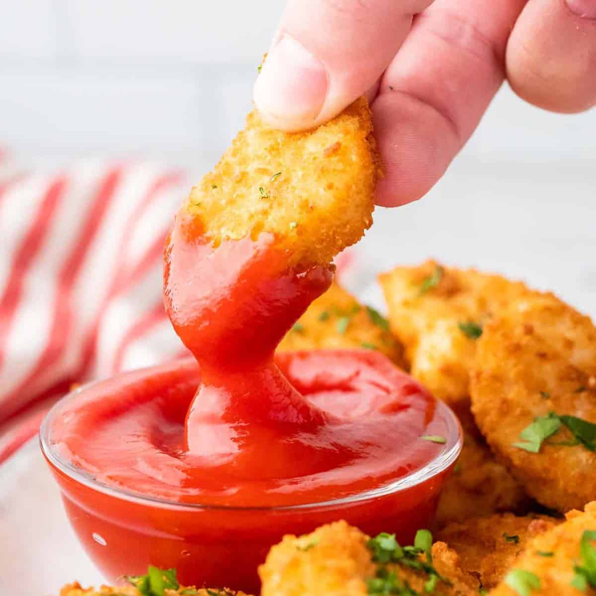 air fried chicken nugget being dipped in ketchup