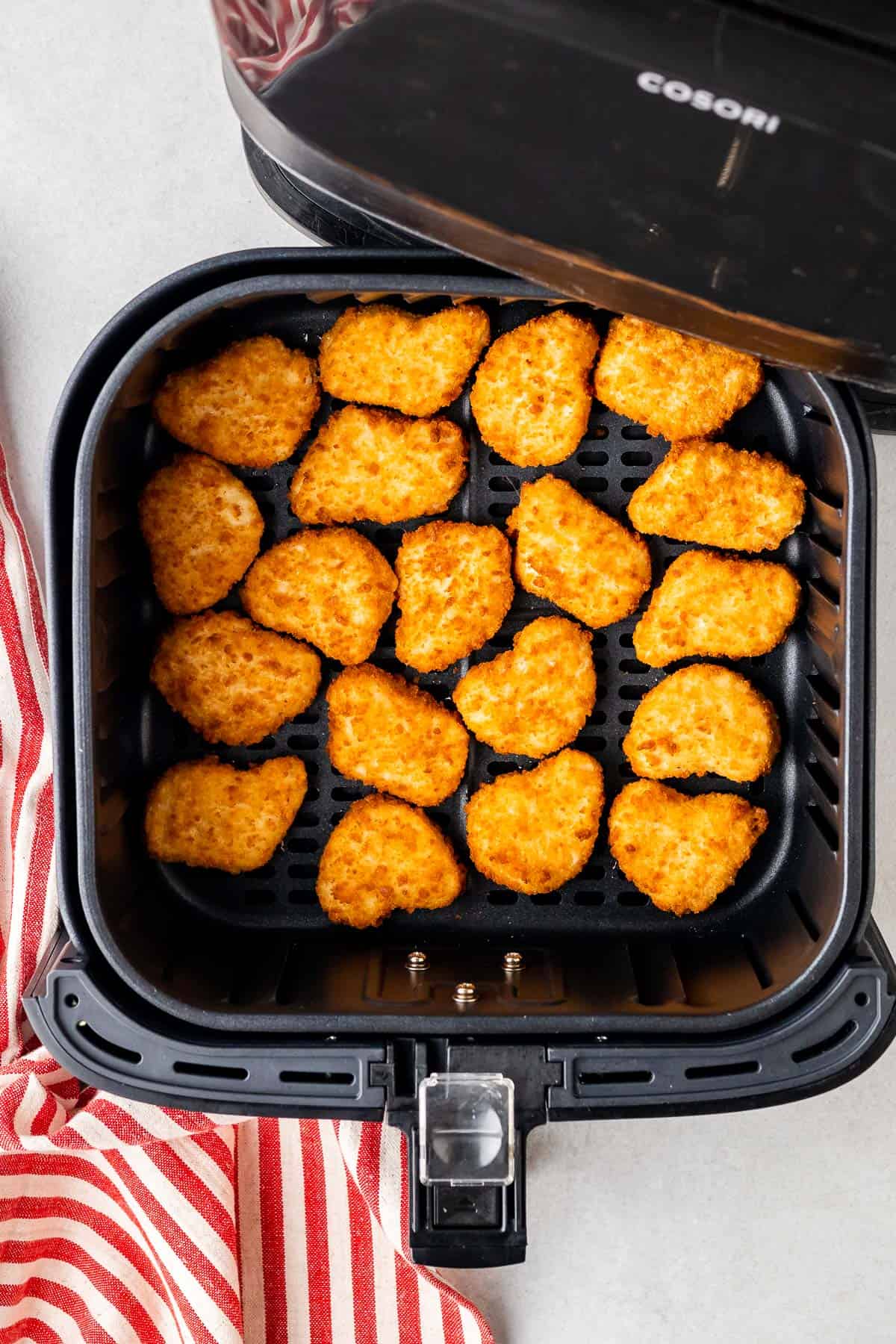 chicken nuggets in the air fryer basket after being flipped halfway through cooking
