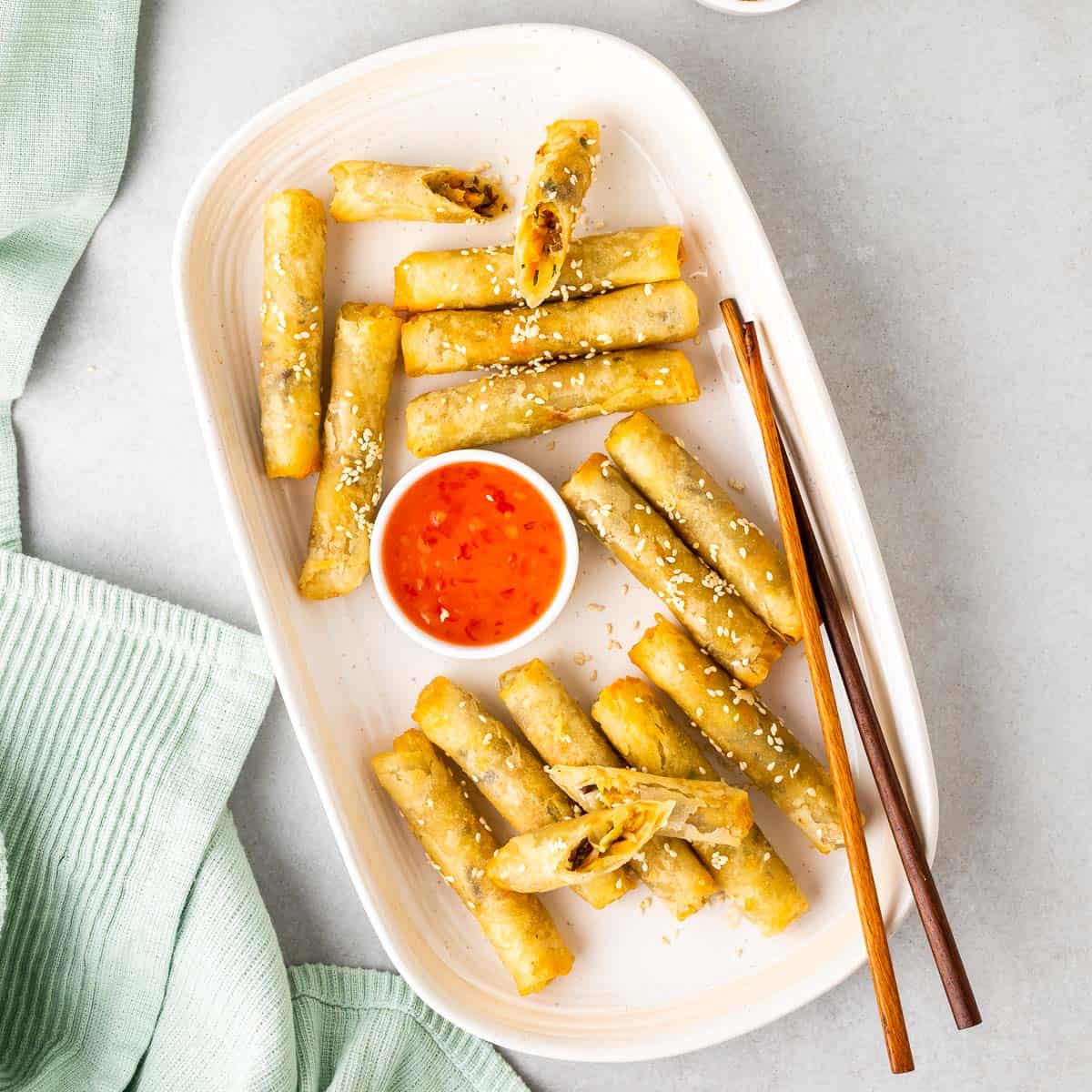air fryer egg rolls on a serving plate with sweet and sour sauce