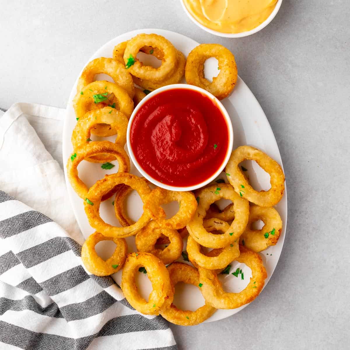 air fried onion rings on a platter, served with ketchup and mustard