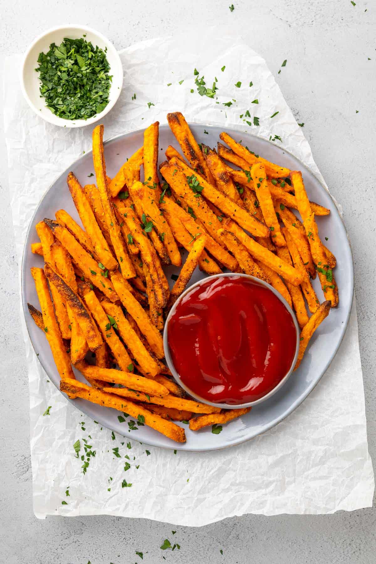 blue plate on parchment paper with sweet potato fries on the plate