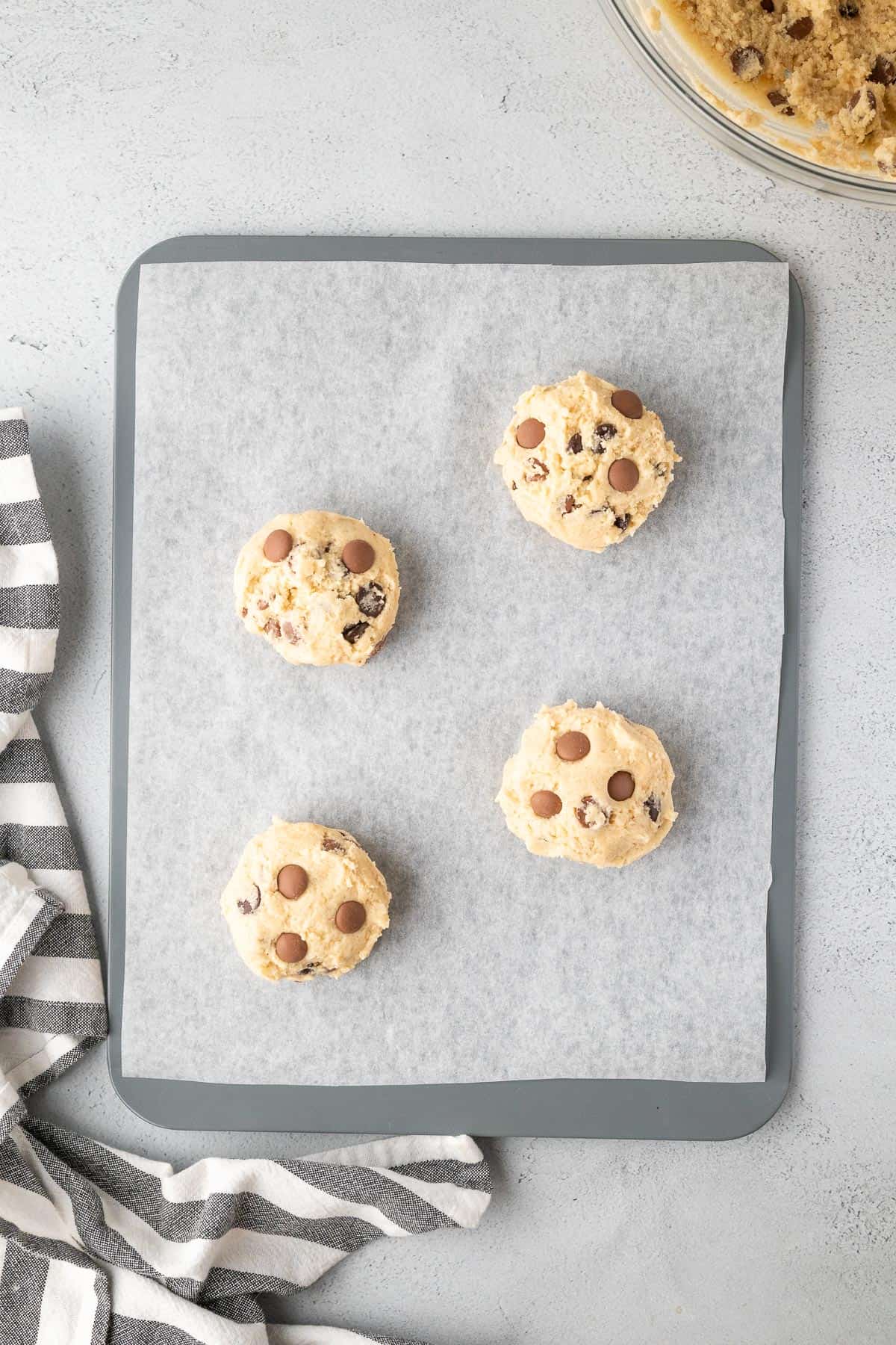 large cookie dough balls on a cookie sheet before baking them