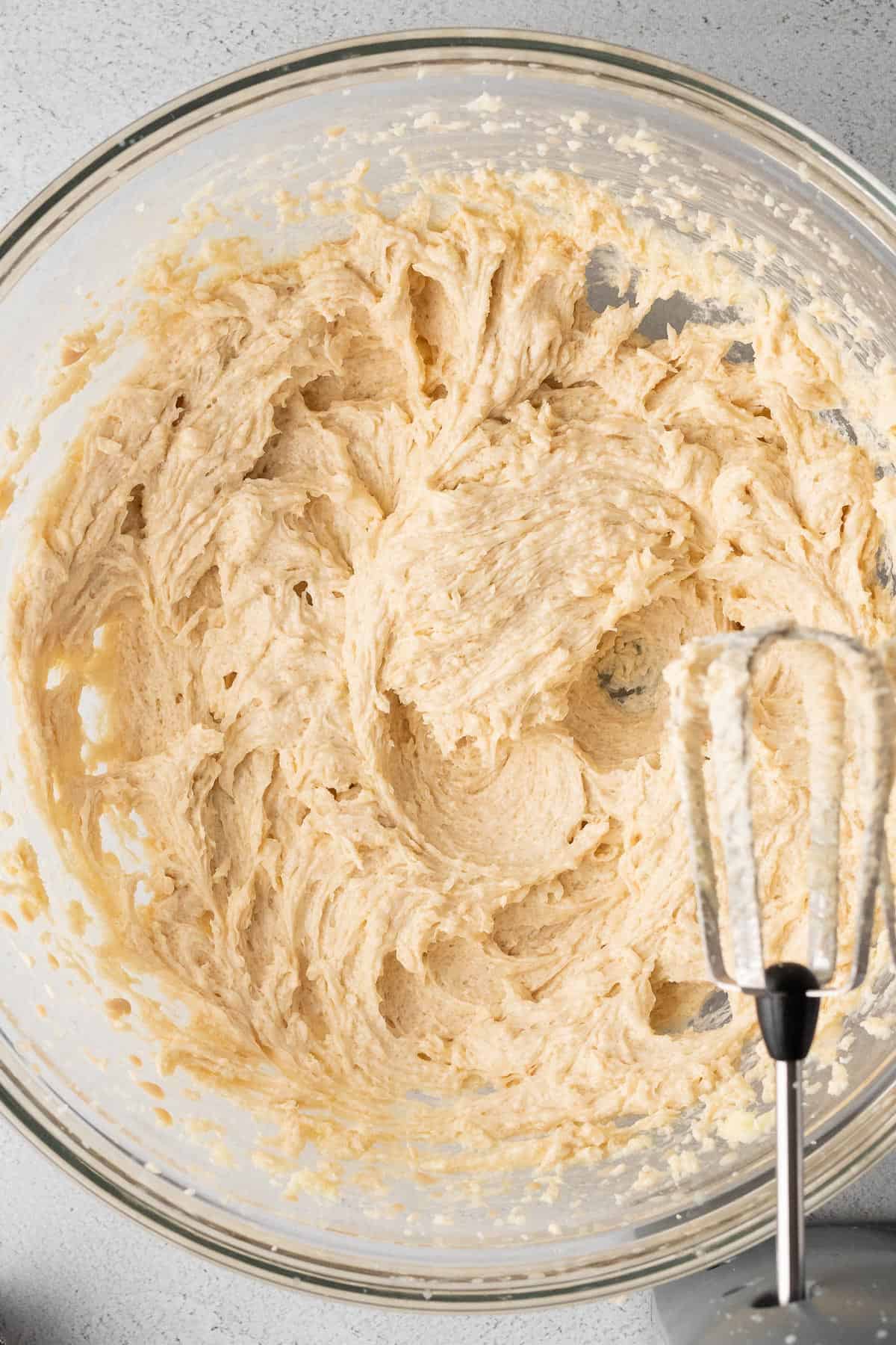 close up of the wet ingredients for the cookies creamed together in a large glass mixing bowl