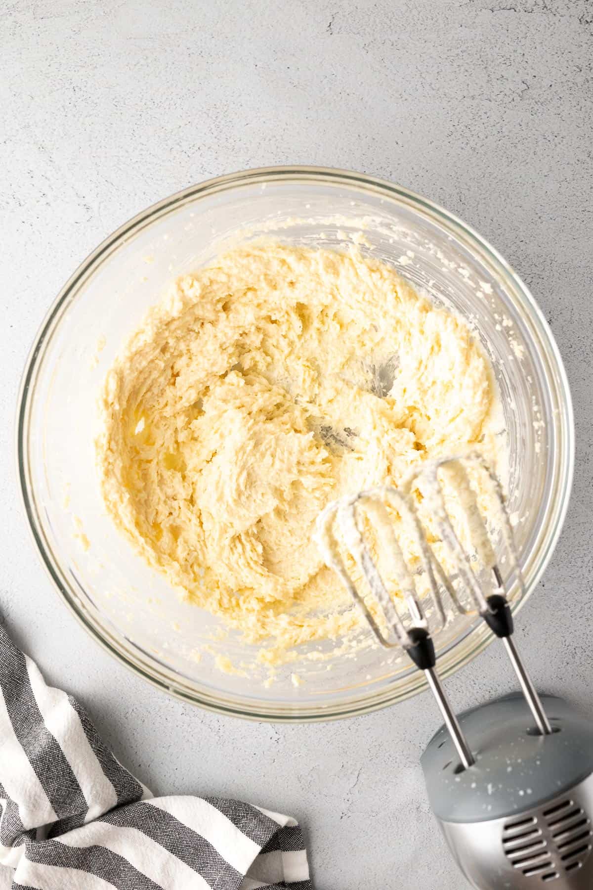 butter and sugars creamed together in a mixing bowl with a handheld mixer