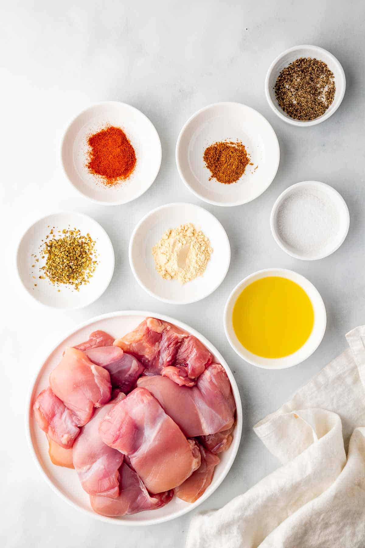 ingredients for the air fryer boneless chicken thighs laid out in white bowls