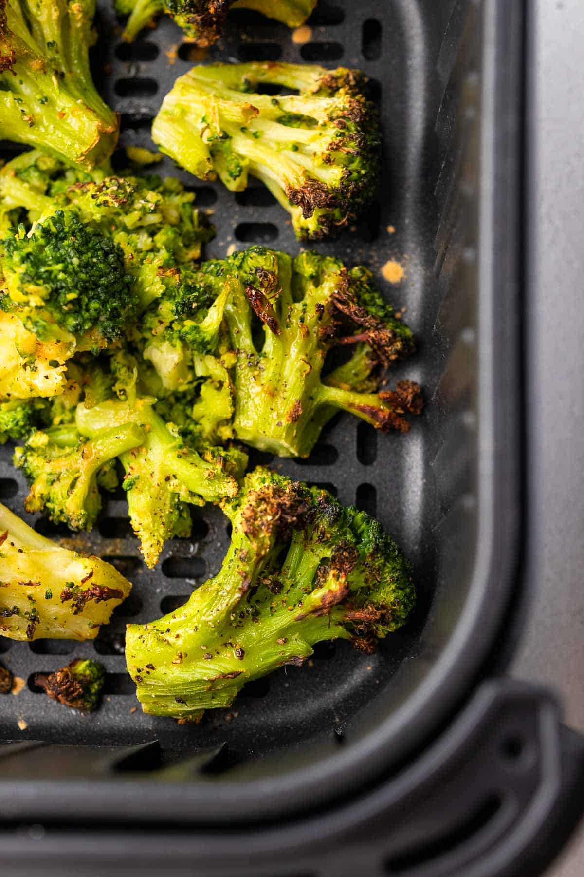 close up on a cooked piece of broccoli in the air fryer basket
