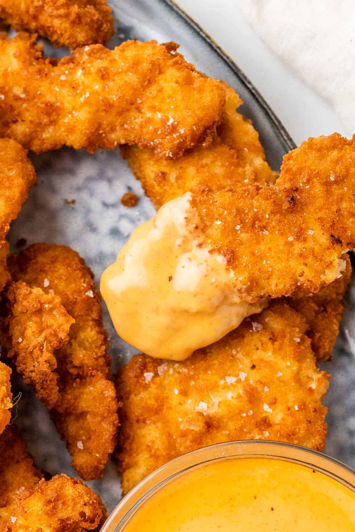 close up of a chicken tender covered with honey mustard sauce