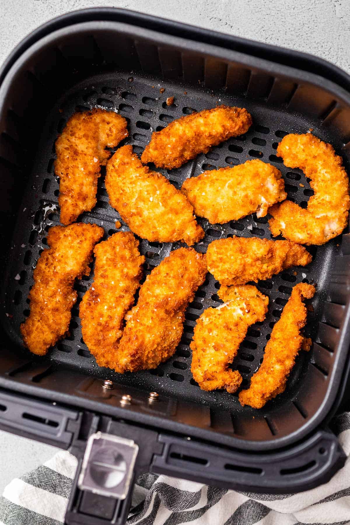 crispy chicken strips in the air fryer basket after cooking