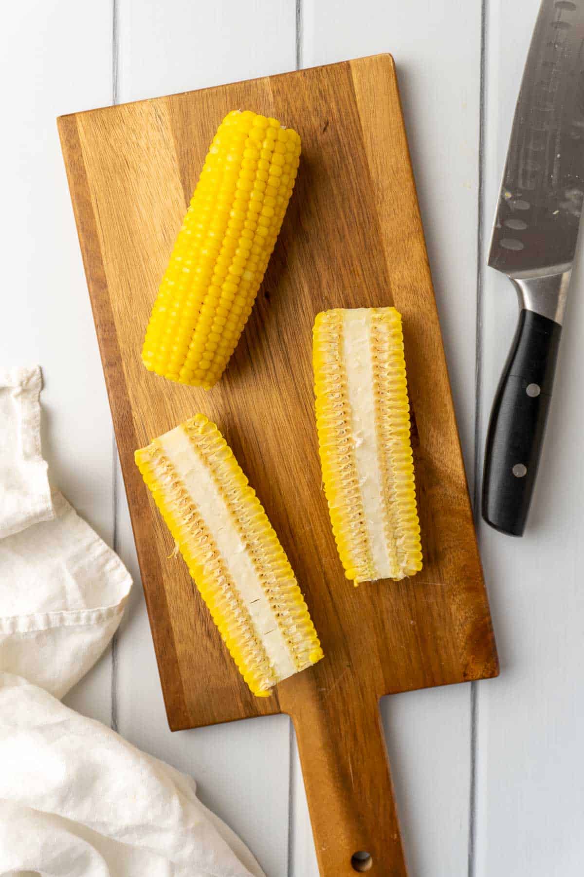 cutting the corn cobs into corn ribs on a wooden board with a white cloth to one side