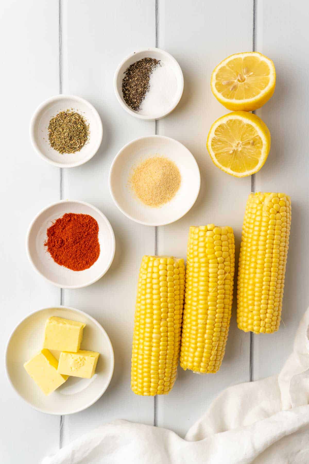 ingredients for the air fryer corn ribs laid out on white planks with a white decorative cloth