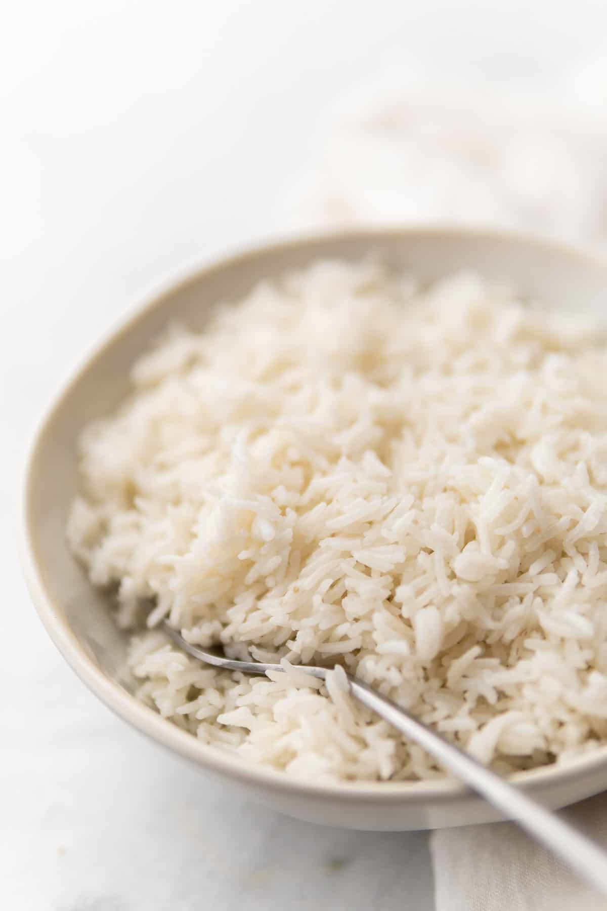side close-up shot of the cooked rice in a grey bowl served with a fork