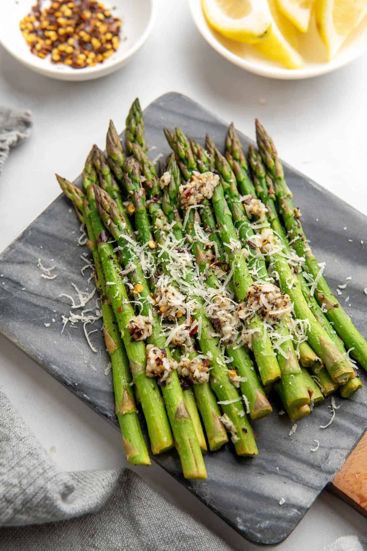 close up of the asparagus served with freshly grated parmesan, lemon wedges and chilli flakes