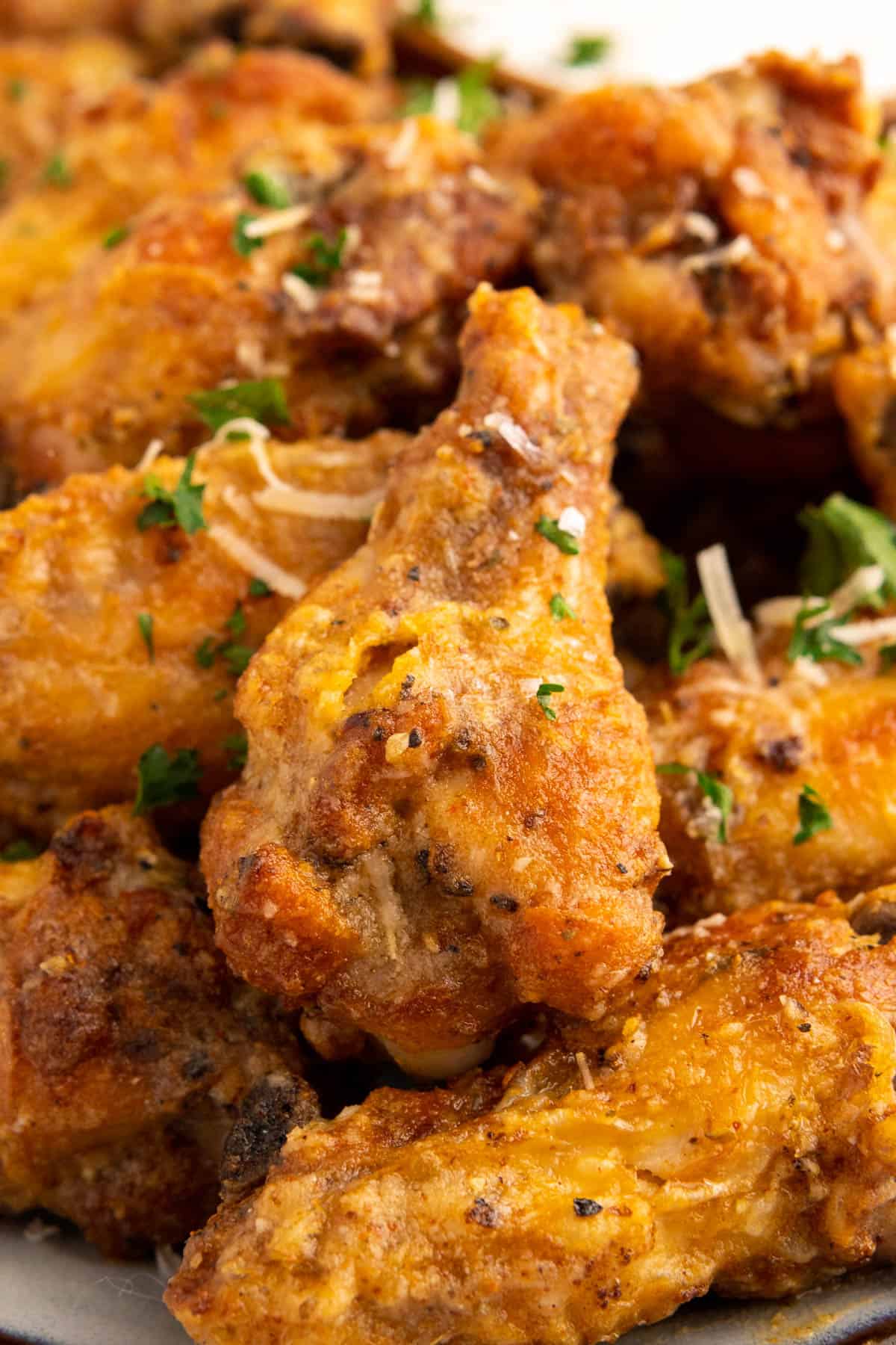 Extreme close up on one of the garlic parmesan wings served with fresh parsley and parmesan