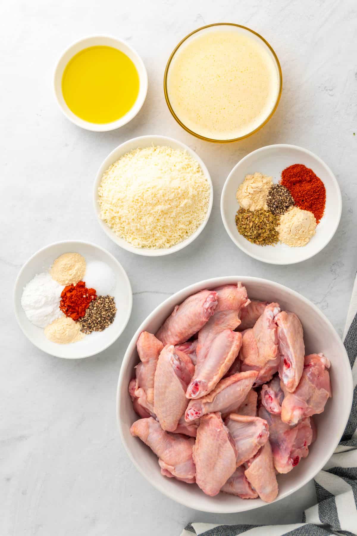 Ingredients for the air fryer garlic parmesan wings laid out in separate white bowls and dishes
