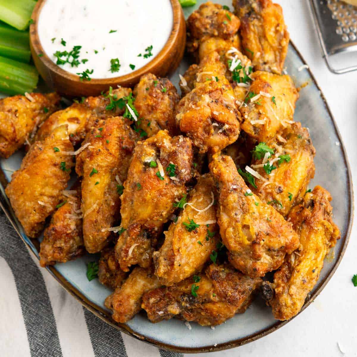 Air fryer garlic parmesan wings on a platter with ranch sauce 