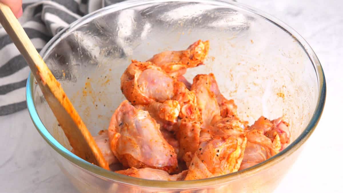 Wings seasoned with spices and herbs being mixed together