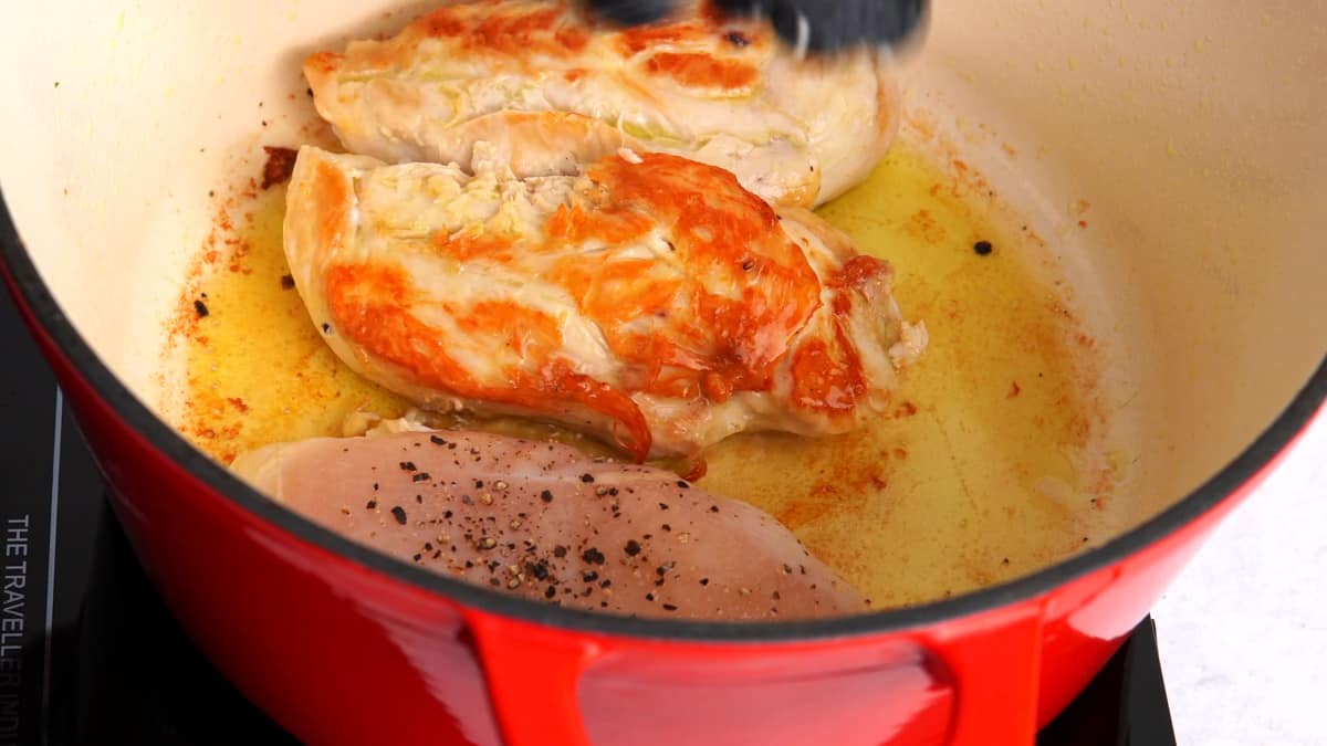 chicken breasts browning in a red pot 