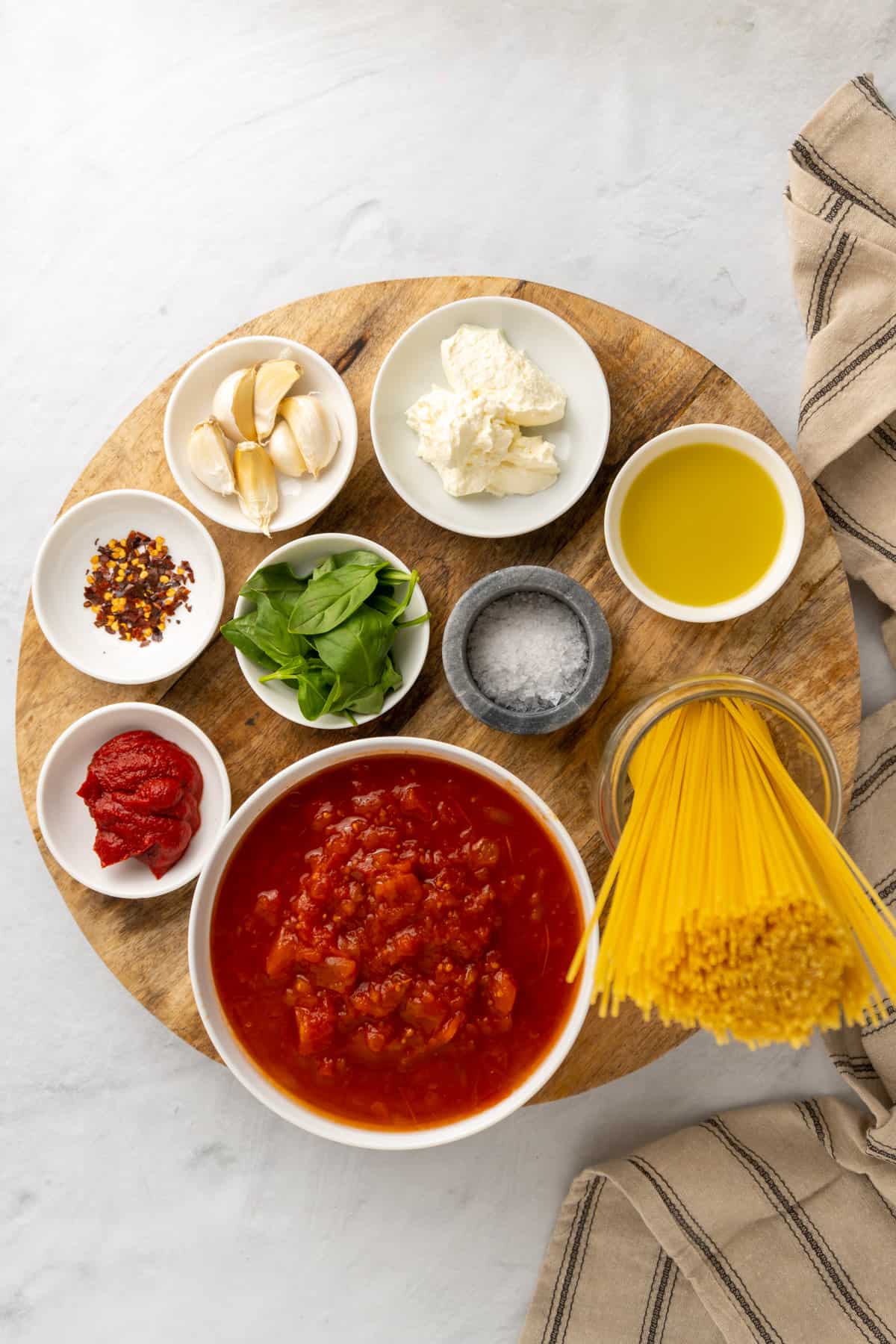 ingredients for the cottage cheese pasta sauce laid out in small dishes on a large wooden board 