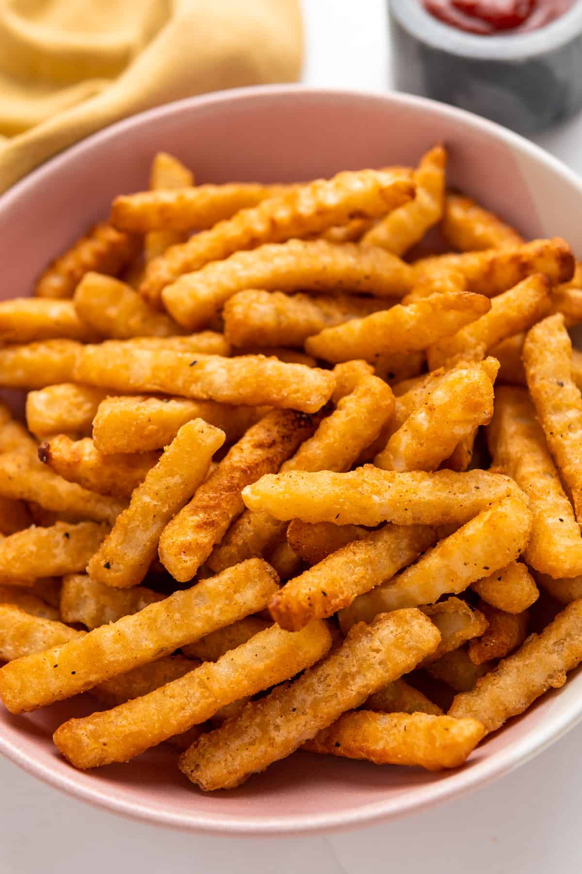 a bowlful of golden and crispy crinkle cut fries served 