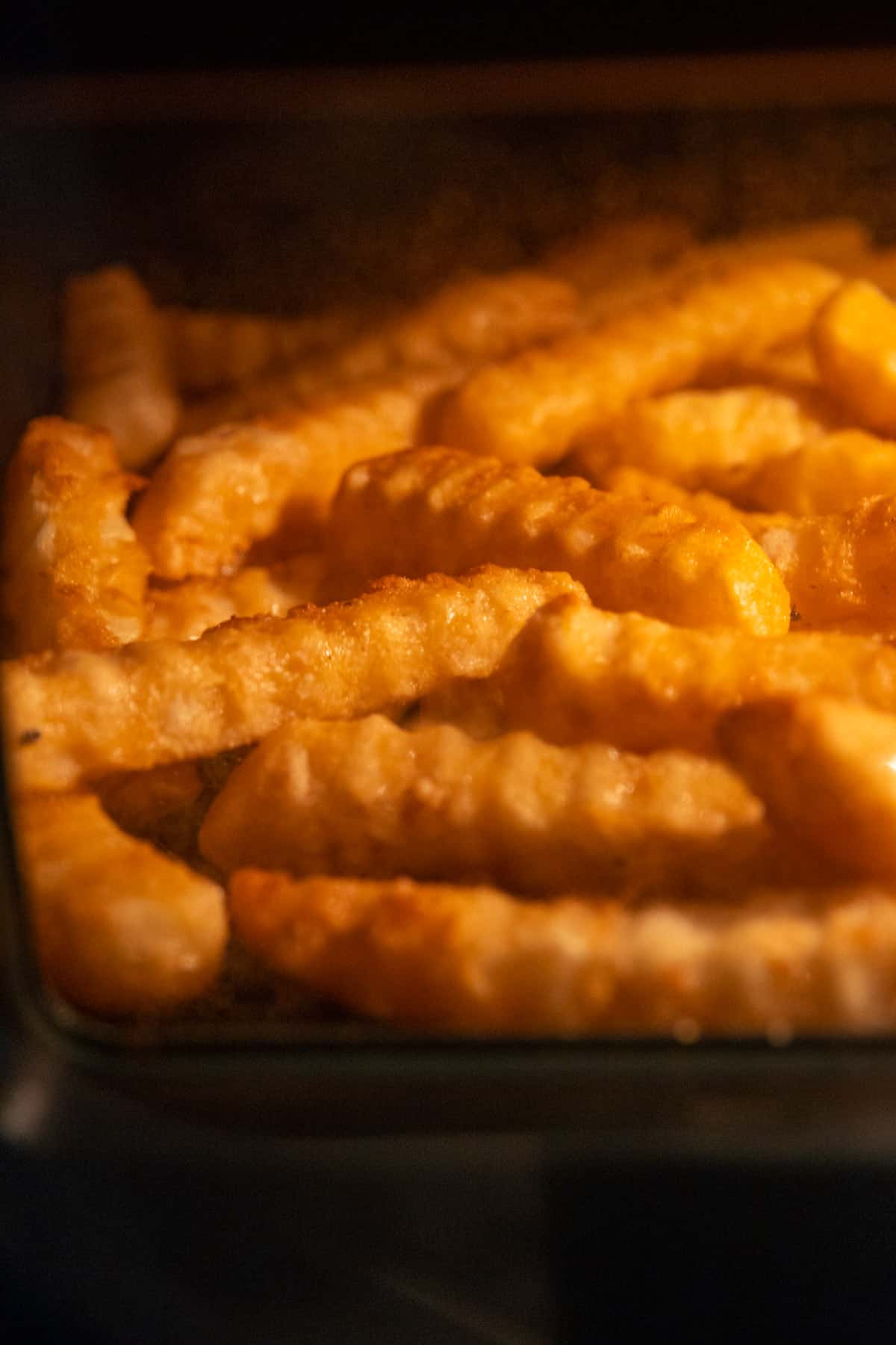 crispy and golden crinkle cut fries in the air fryer while cooking 