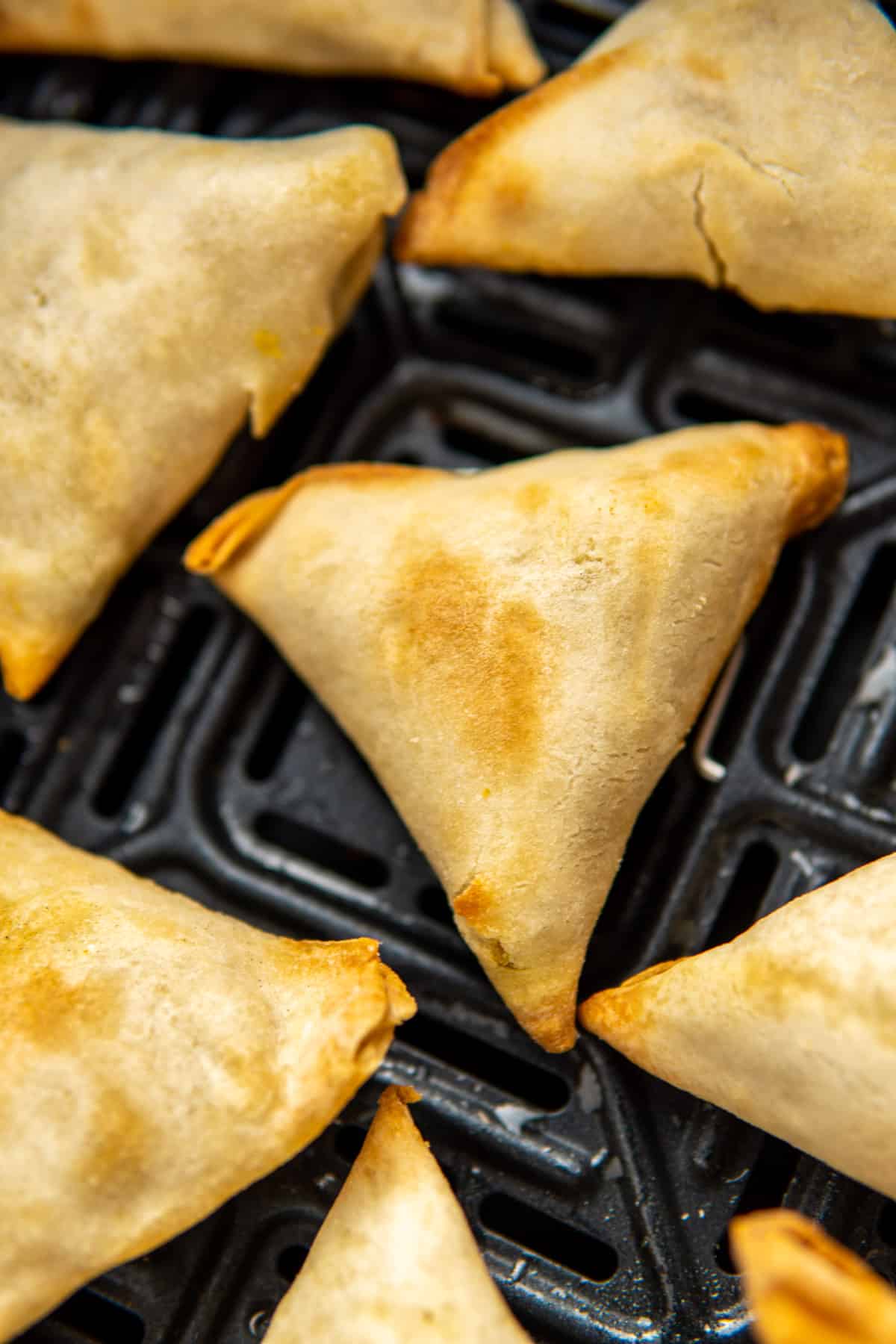 close up of crispy samosa in the air fryer basket