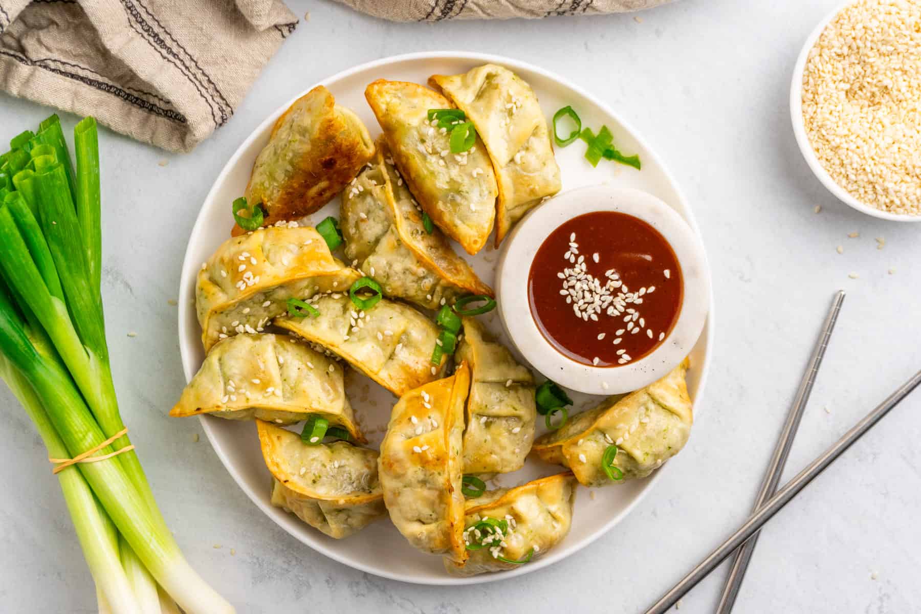 air fried mini wontons in a plate garnished with sesame seeds and green onions