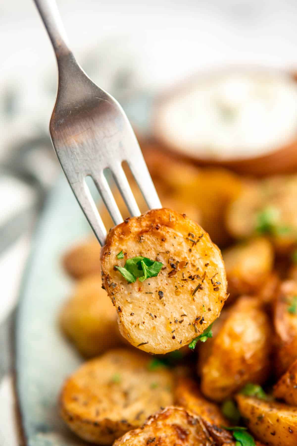 Air fryer greek potato on a fork with some fresh herbs garnished on top. 