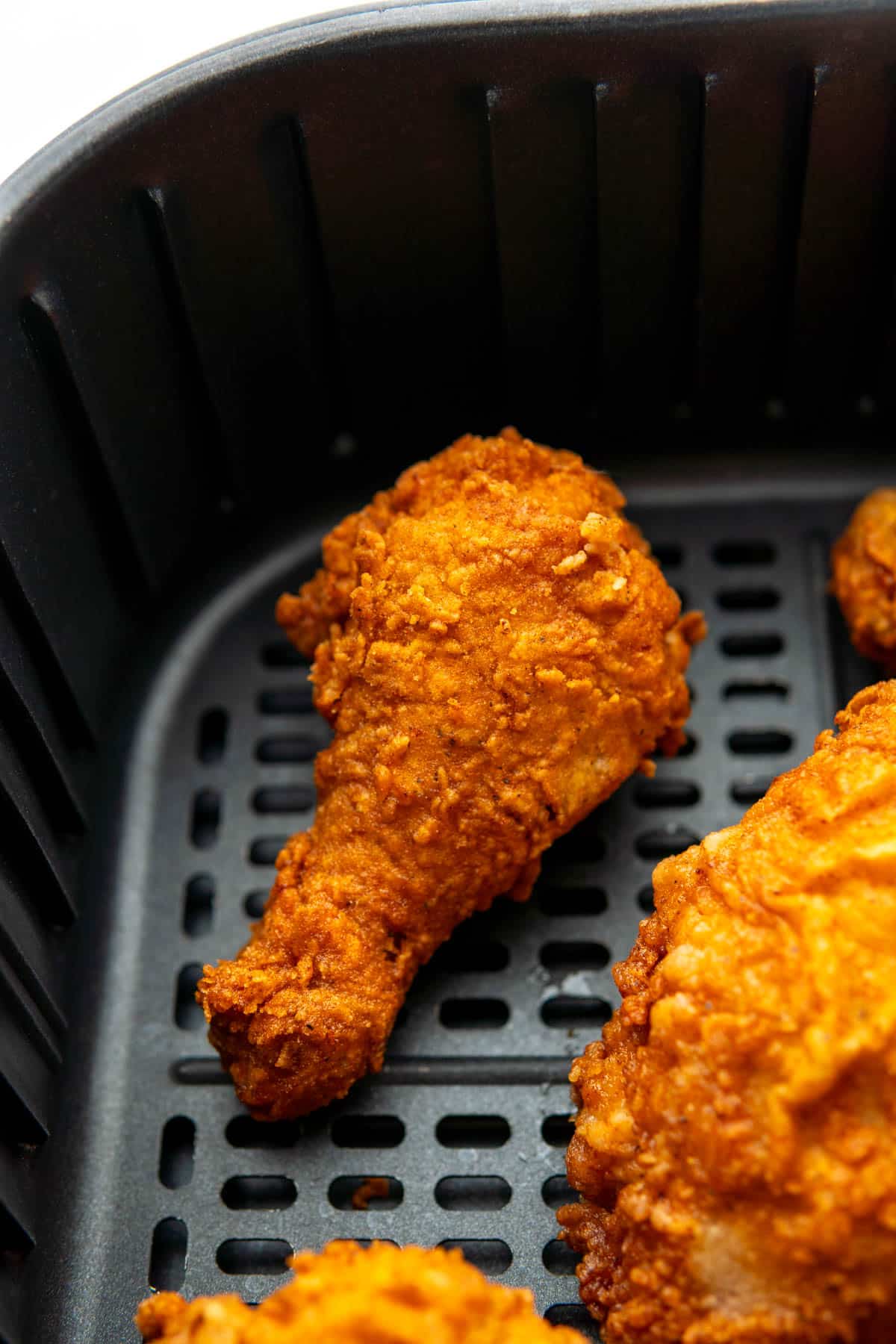 A fried chicken drumstick in the air fryer basket before being reheated. 