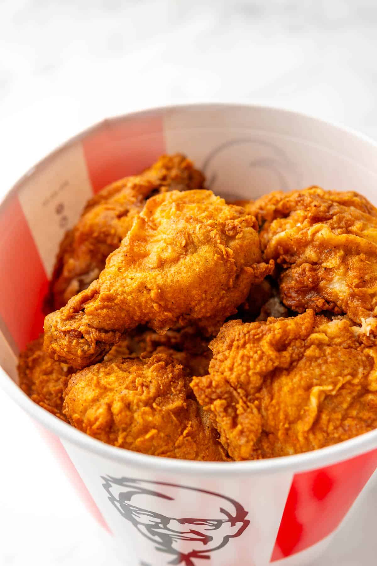 A close up of a pile of fired chicken in a KFC bucket. 