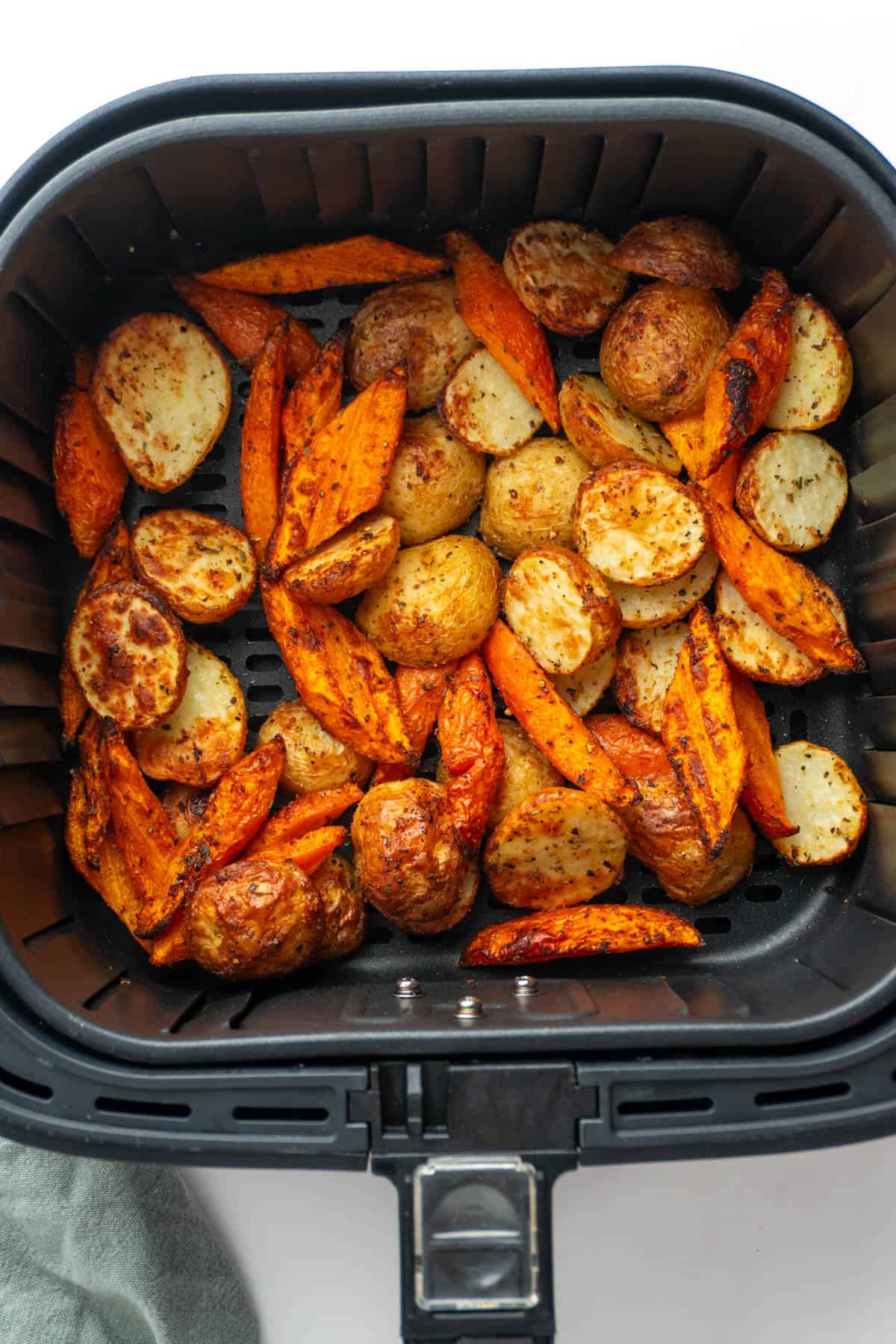 Golden and crispy roasted carrots and potatoes in the air fryer basket. 