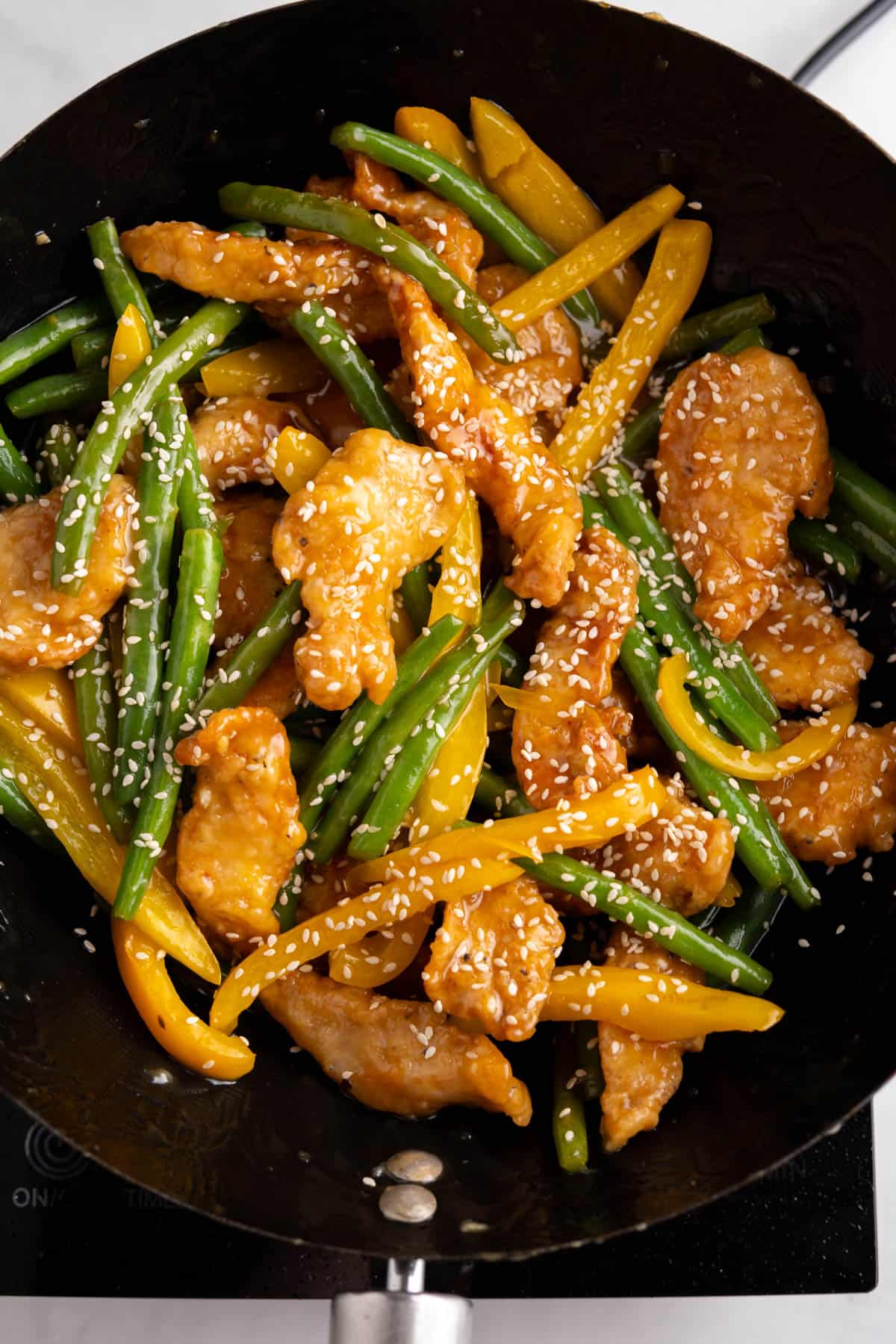 The Panda Express sesame chicken in a large wok garnished with sesame seeds. 