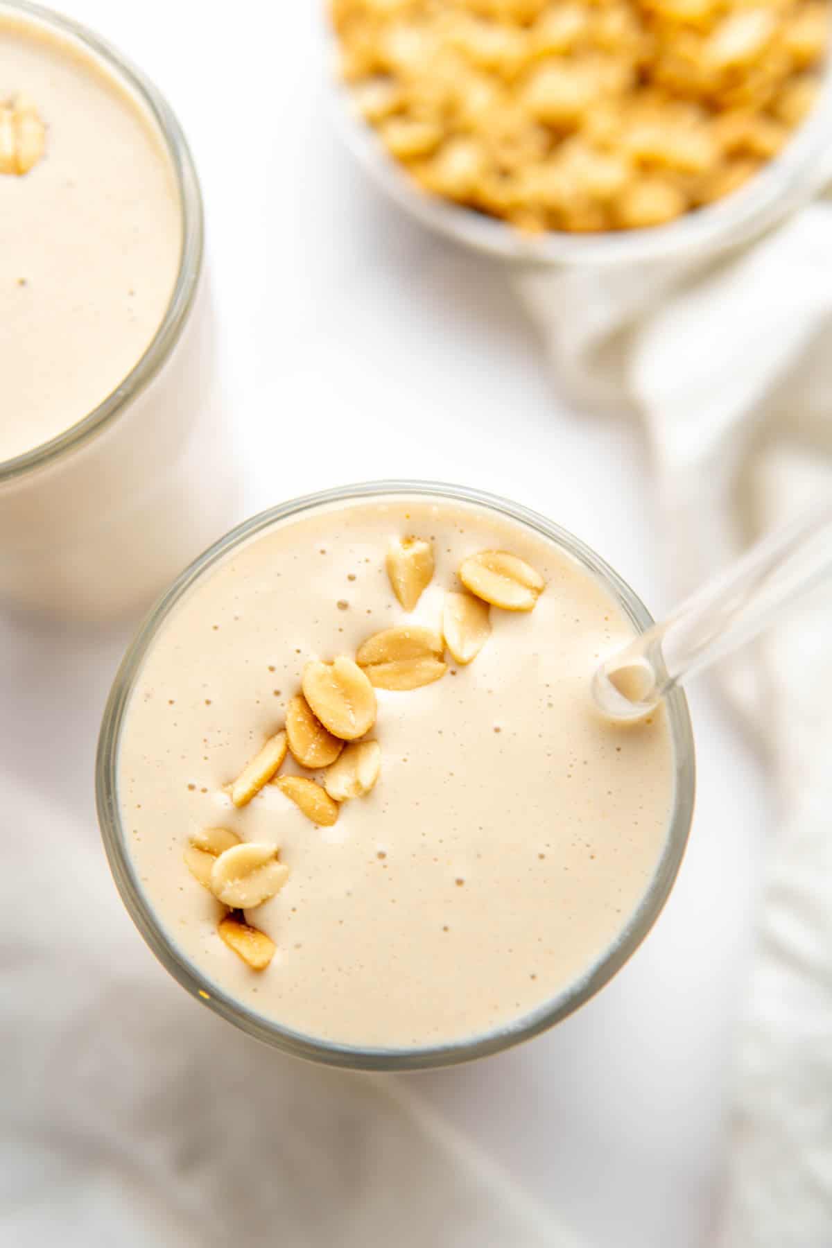 Top of the smoothie glass with the thick smoothie in a glass, garnished with some peanuts. 